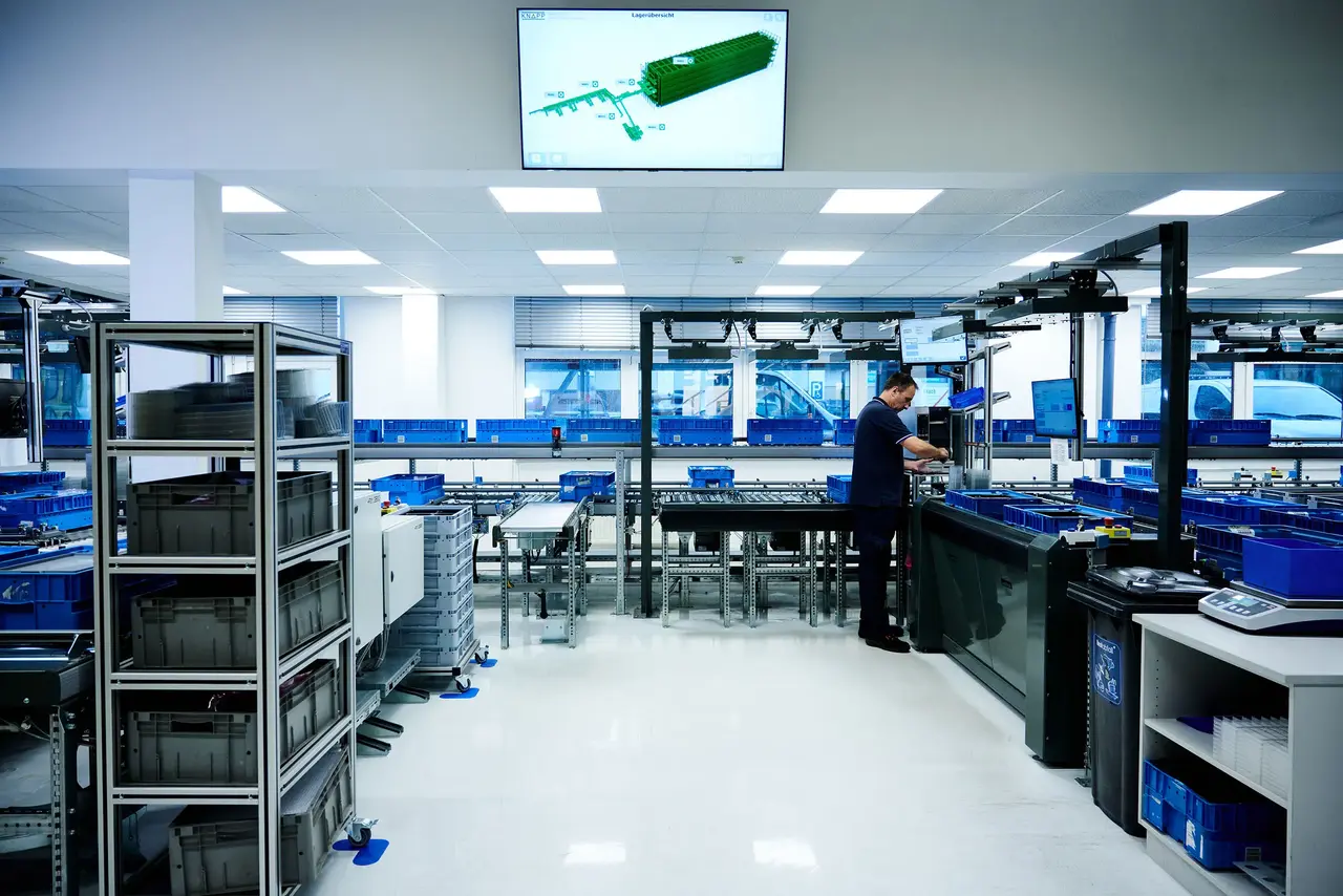 Warehouse automation workstation with bins, conveyors and operators