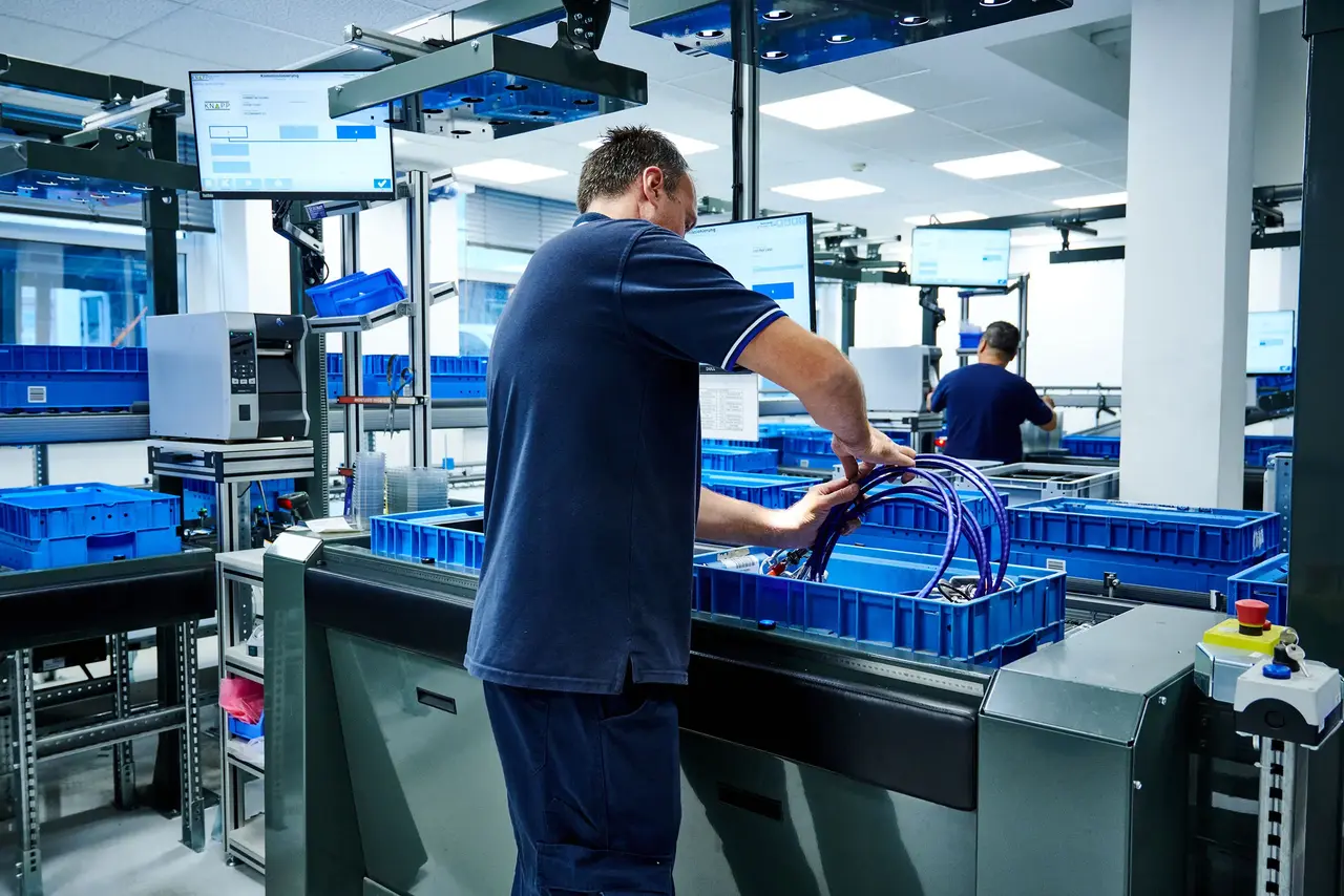 Operator handling bins at an automated warehouse workstation